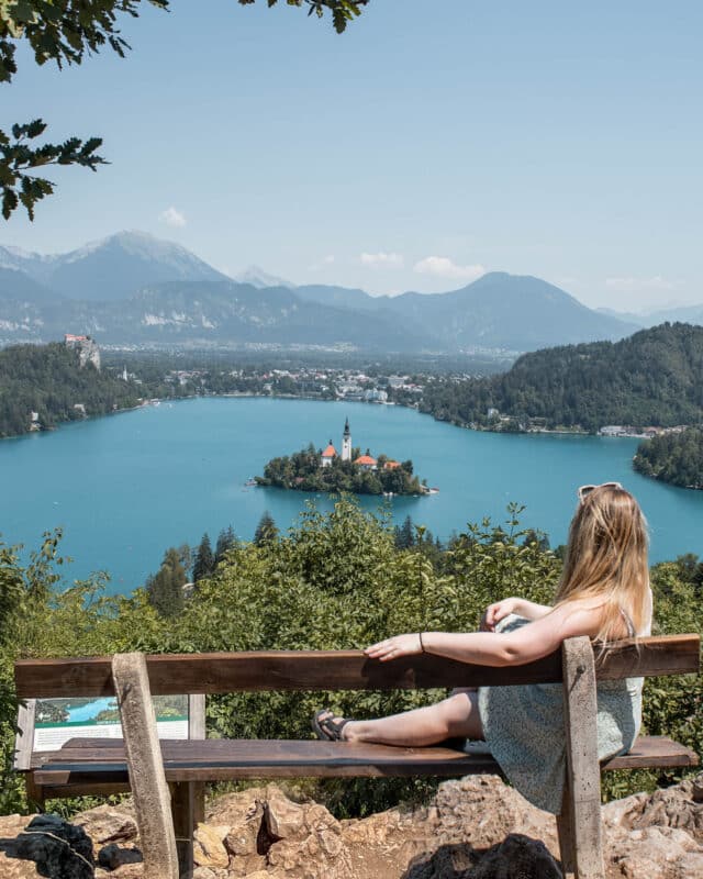Girl sitting on a bench looking at the view of lake bled. An alpline lake in Slovenia