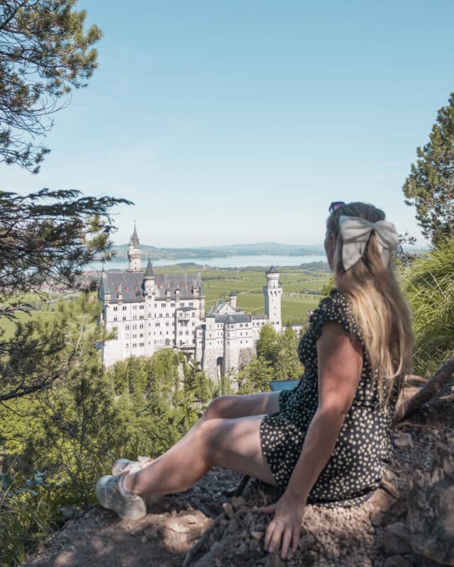 Girl sitting at a viewpoint of the fairytale castle of Neuschwanstein in Germany