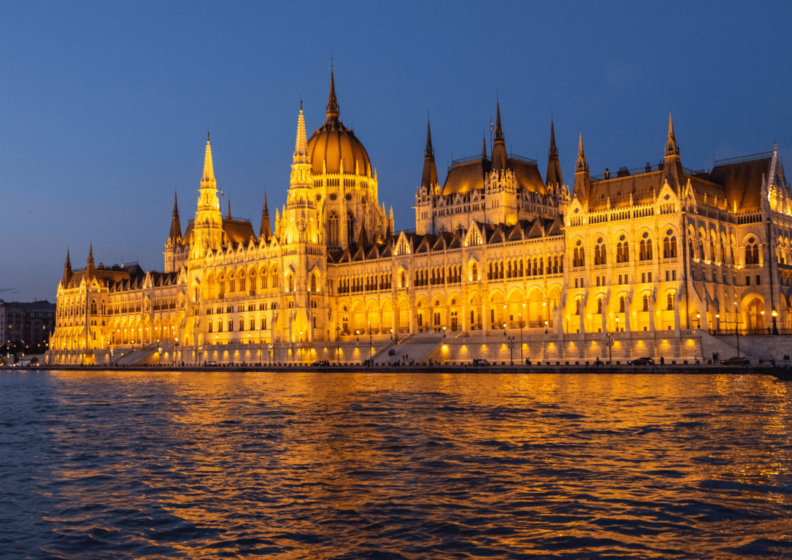 Budapest Parliament Building lit up at night shinning into the Danube